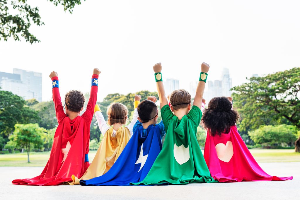 kids in superhero costumes with their arms raised in victory