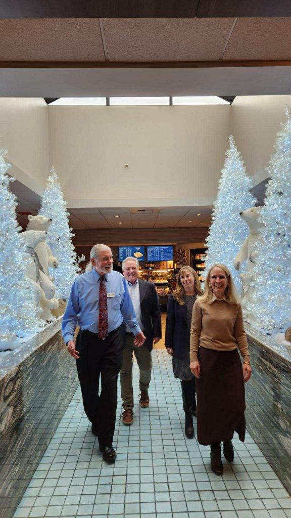 four people walking through christmas decorations and smiling