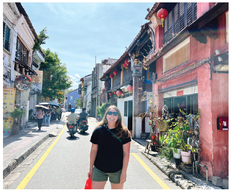 Photo of Carissa Carns in Malaysia city street with motorcycle in the background.