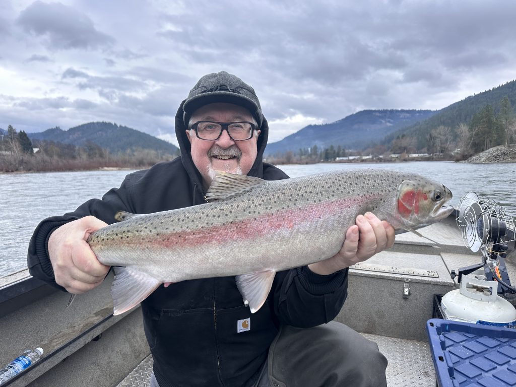 Man smiling in boat with fish.