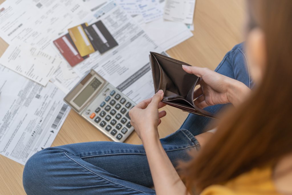 woman sitting on the floor with a calculator with forms and an empty wallet