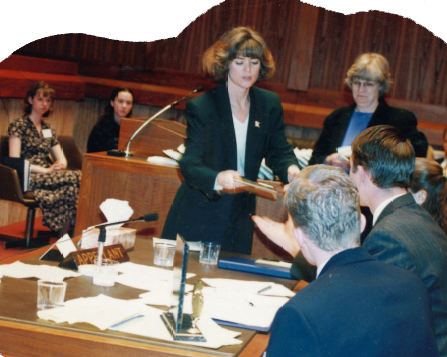 Diane in courtroom handing documents to students.