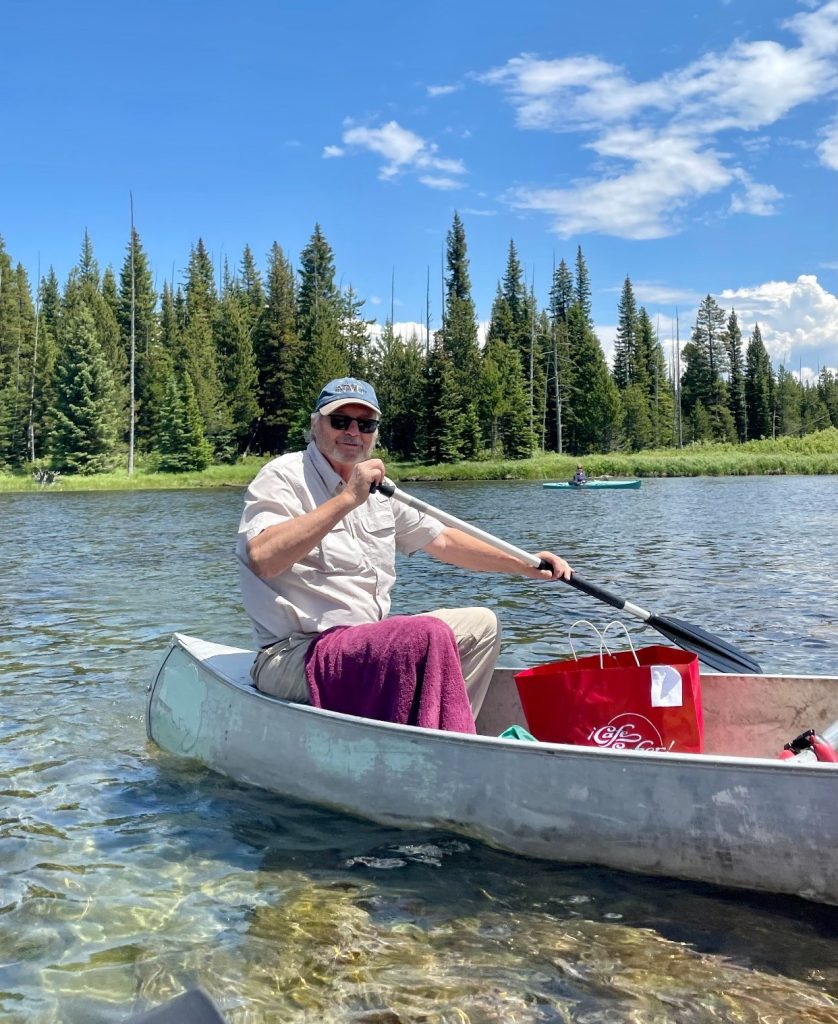 man smiling in canoe in river outdoors