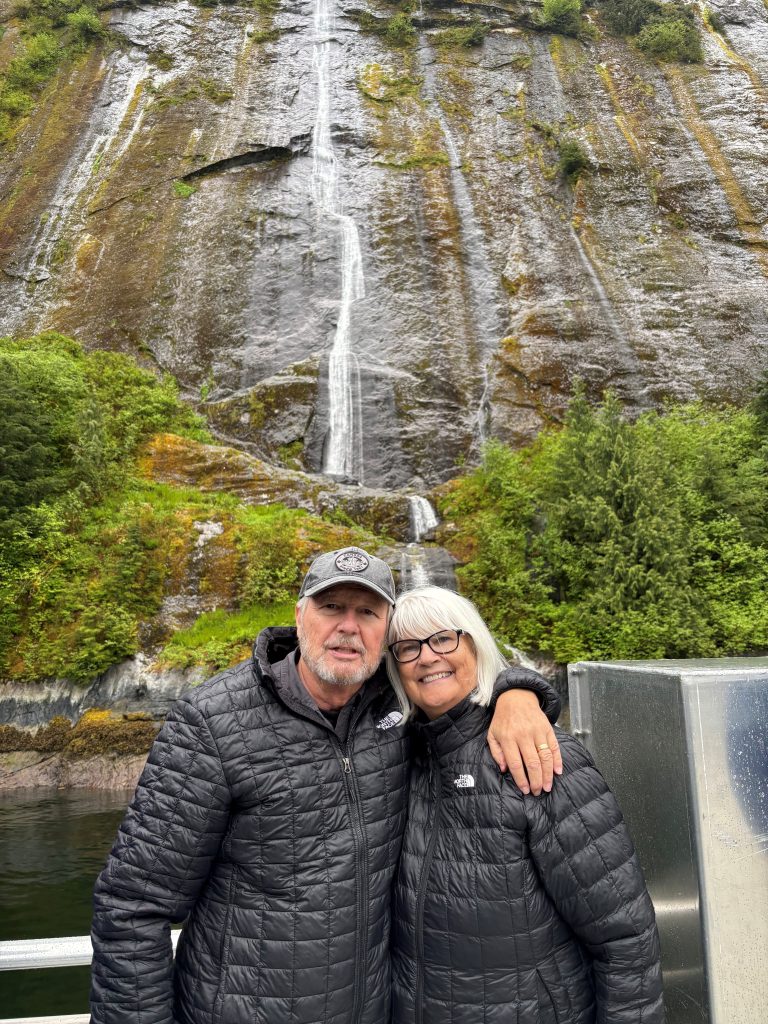man and woman smiling in front of a waterfall in winter coats