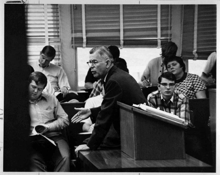 black and white image of man teaching students in classroom
