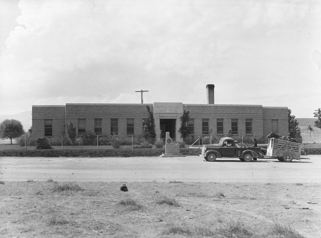 courthouse with old truck driving in front. black and white image