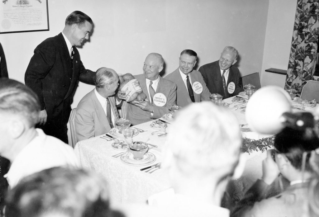 group of men in meeting with suits and nametages on, black and white image