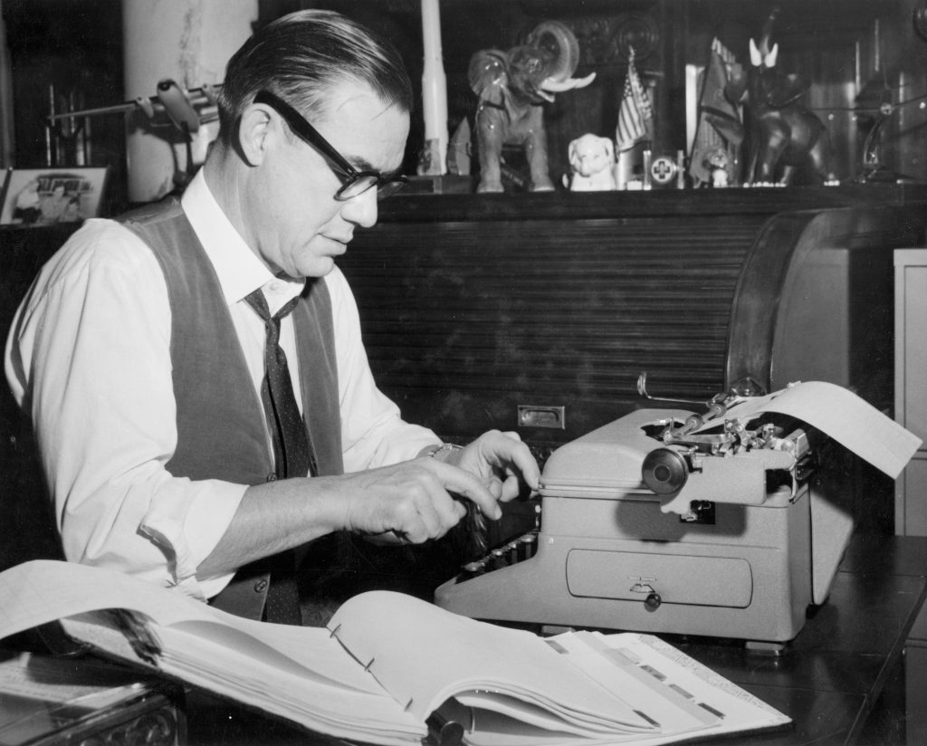 man in office typing on typewriter