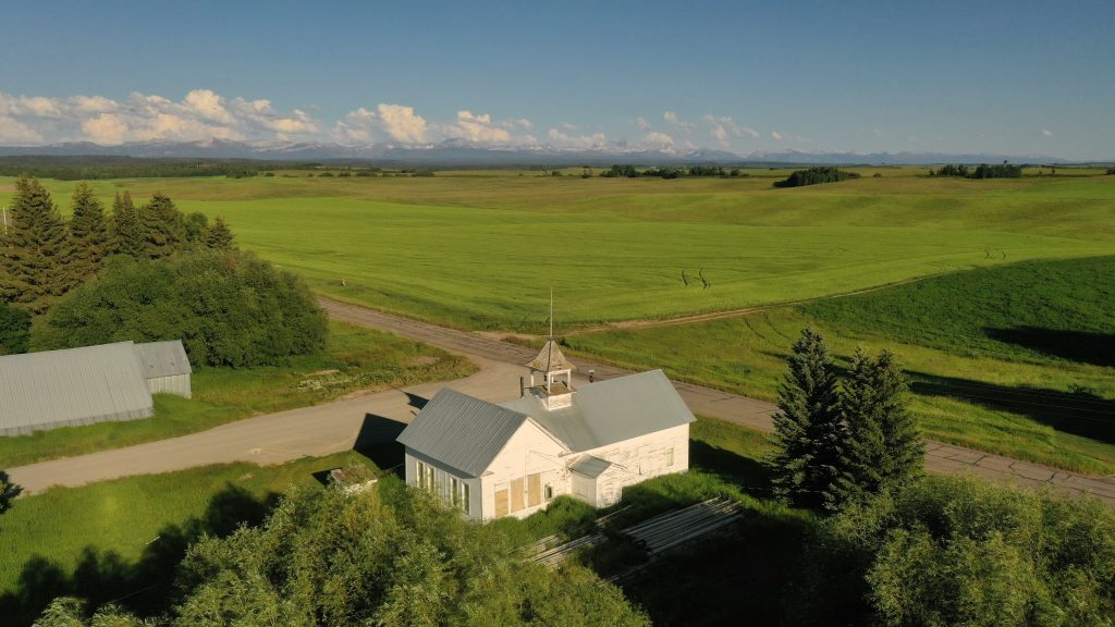 old schoolhouse sitting in green fields