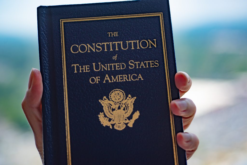 The Constitution of The United States of America book in hand on blurred background. Closeup cover view.