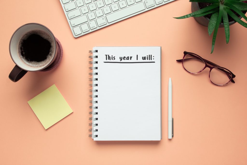 Stock photo of new year notebook with list of resolutions and objects on pink background