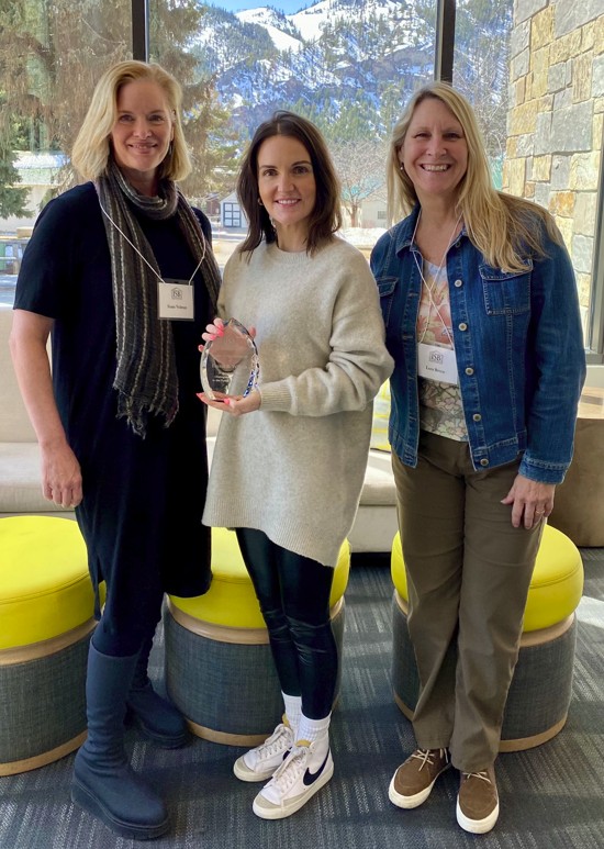 three women standing inside with an award