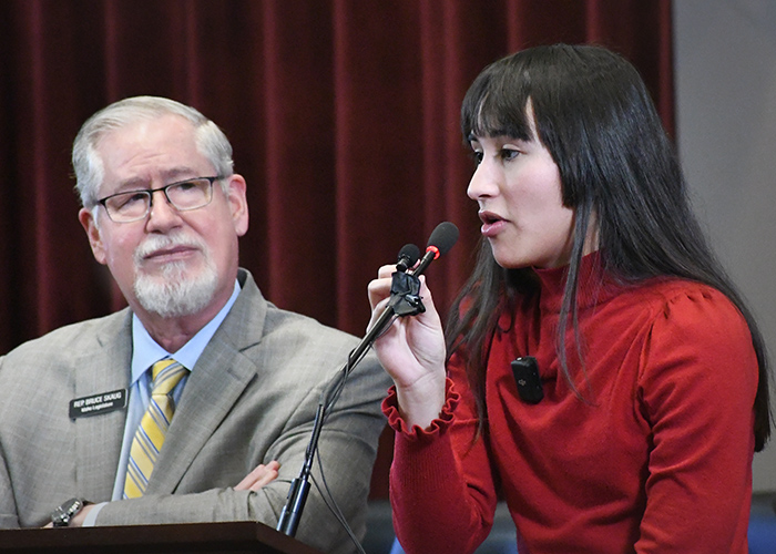 man looking at woman, woman speaking at microphone inside
