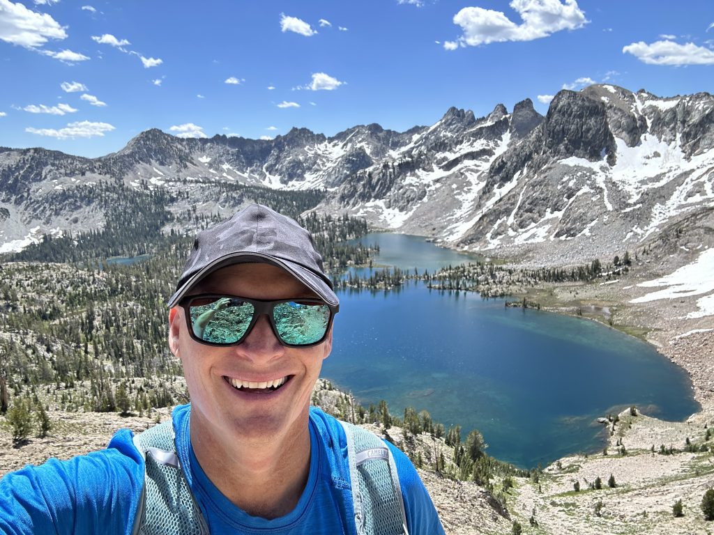 man smiling in front of mountain lake